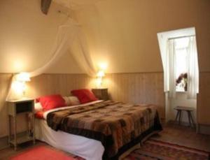 a bedroom with a bed with red pillows and a window at Le Moulin Fleuri du Petit Appeville in Petit-Appeville