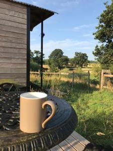 una tazza di caffè seduta su un tavolo con una ruota di Wellbank Shepherds Hut a Chetwynd