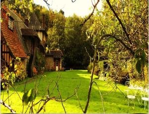 a yard with a house and a lawn with chairs at Le Moulin Fleuri du Petit Appeville in Petit-Appeville