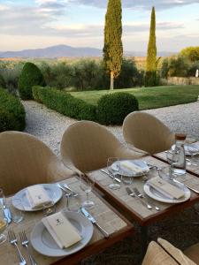 einen Holztisch mit Stühlen, Tellern und Weingläsern in der Unterkunft Fontelunga Hotel & Villas in Pozzo