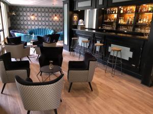 a restaurant with a bar with chairs and tables at Hotel Le Cardinal Rueil Centre in Rueil-Malmaison