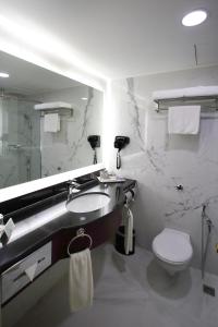 a bathroom with a toilet a sink and a mirror at Corus Hotel Kuala Lumpur in Kuala Lumpur