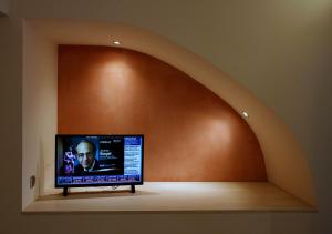 einen Flachbild-TV in einem Zimmer mit einem Torbogen in der Unterkunft Katrine Boutique Apartments in Kavala