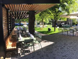 un patio con tavoli, sedie e un albero di Hotel Maxlhaid a Wels