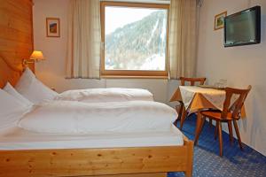 a bedroom with two beds and a table and a window at Alkira in Sankt Anton am Arlberg
