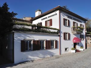 ein weißes Gebäude mit einer roten Markise auf einer Straße in der Unterkunft Hotel Bonconte in Urbino