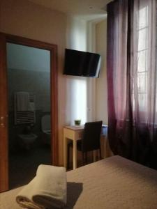 una camera con letto, scrivania e specchio di Albergo Torino ad Albenga