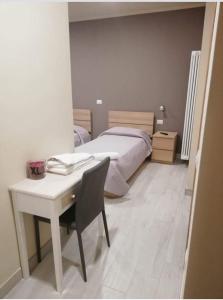 a bedroom with a bed and a desk with a table and a chair at Albergo Torino in Albenga