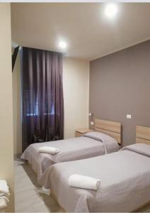 una camera con due letti e una finestra con tende viola di Albergo Torino ad Albenga