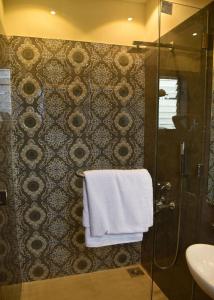 een badkamer met een douche en een witte handdoek bij Creek Hotel in Panaji