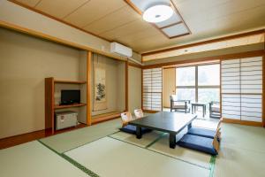 un soggiorno con tavolo, sedie e TV di kinugawaonsen Fukumatsu a Nikko