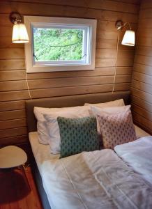 a bed with two pillows in a room with a window at Solbakken Cabins in Geiranger