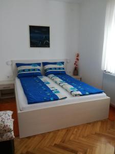 スヴェティ・マルティン・ナ・ムリにあるApartmani Oletić 4*の白いベッド(青いシーツ、枕付)