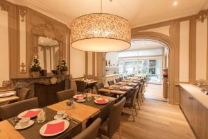 a dining room with tables and chairs and a chandelier at Hotel de Flandre Ghent in Ghent