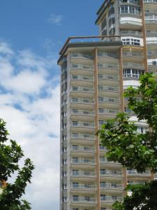 un edificio de apartamentos alto con árboles en el primer plano en Apartamentos Playamar, en Benidorm