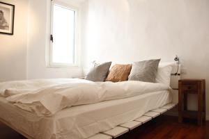 un letto bianco in una camera bianca con finestra di Art Apartment Velluti a Firenze