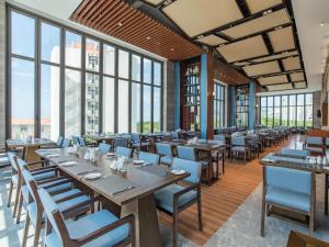 un restaurante con mesas y sillas de madera y ventanas en Sanya Dadonghai Hotel, en Sanya