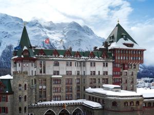 a large building with snowy mountains in the background at Badrutt's Palace Hotel St Moritz in St. Moritz