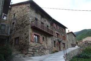 un antiguo edificio de piedra con balcón en una calle en Apartaments Can Bundanci, en Setcases