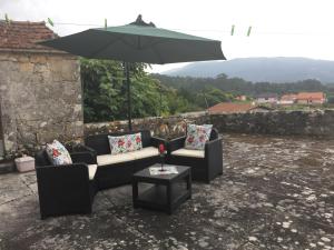 un patio con 2 sofás y una mesa con sombrilla en Casa do Carqueijo, en Vila Praia de Âncora
