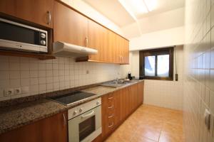 a kitchen with wooden cabinets and a microwave at Pont de Toneta 5,2 Ransol, Zona Grandvalira in Ransol