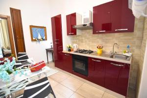 uma cozinha com armários vermelhos, uma mesa e um lavatório em Sunrise B&B em Nápoles