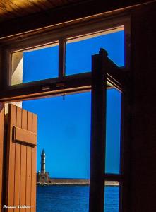 une fenêtre avec vue sur un phare dans l'eau dans l'établissement Villa Venezia, à La Canée