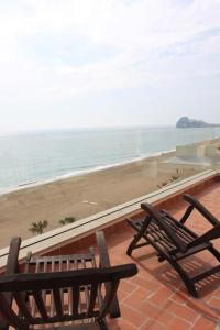 two benches sitting on a balcony looking at the beach at Apartamentos Florida II in Peñíscola