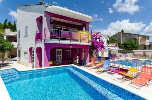 a house with a swimming pool in front of a house at Beachfront villas Pinky-Superior heated pools and jacuzzi just 25 m from see in Seget Vranjica