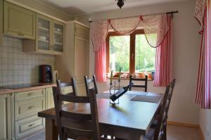 uma cozinha com uma mesa de madeira com cadeiras e uma janela em Dom Na Pstrążnicy em Kudowa-Zdrój