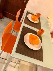 una mesa de cristal con dos platos y sillas naranjas en Bonito Loft D. Pedro Life, en Sevilla