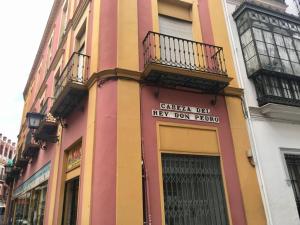 un edificio amarillo y rosa con un cartel en él en Bonito Loft D. Pedro Life, en Sevilla