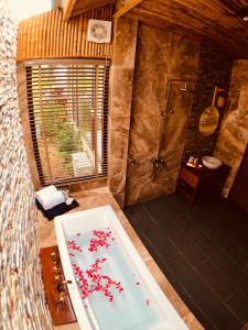 a bathroom with a bath tub with red flowers in it at Coral Bay Resort in Phú Quốc