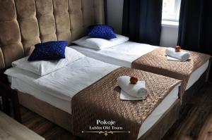 two beds in a hotel room with towels on them at Lublin Old Town Rooms in Lublin