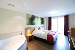 a bedroom with a tub and a bed and a bath tub at Christiana's Wein & Art Hotel in Bernkastel-Kues