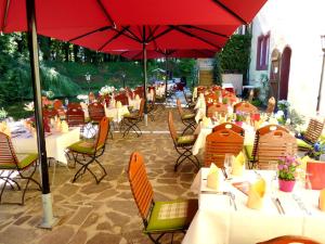 a row of tables and chairs with red umbrellas at Hotel & Spa Wasserschloss Westerburg in Westerburg