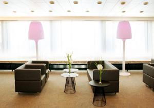 una sala d'attesa con divani, tavoli e ampie finestre di AVIA Hotel a Ratisbona