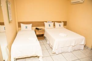 Barra do CordaHotel Diniz的小客房内的两张床,配有白色床单