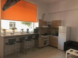 a kitchen with a white refrigerator and some bar stools at Sisifou Hostel in Korinthos