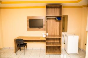 a room with a desk and a television and a refrigerator at Hotel Diniz in Barra do Corda