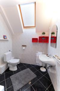 a white bathroom with a sink and a toilet at Family Garden Apartmanház in Siófok
