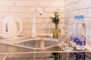 a kitchen counter with a sink and two bottles and glasses at GoldenEye Apartment Center in Wrocław