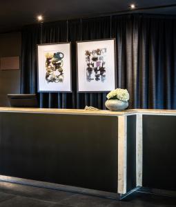 a counter with three pictures on the wall and a vase at AMERON Luzern Hotel Flora in Lucerne