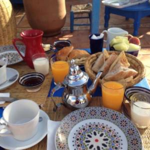a table with a breakfast of bread and orange juice at La Maison Du Vent in Essaouira