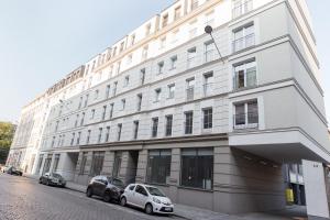 um edifício branco com dois carros estacionados em frente em GoldenEye Apartment Center em Breslávia