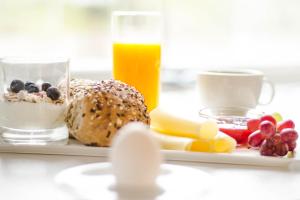 een bord met kaas en fruit en een glas sinaasappelsap bij Bardufoss Hotell in Bardufoss