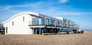 a building on the beach with people walking around it at Amazing beach apartment in Lancing