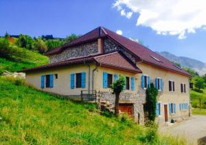 une maison avec des fenêtres bleues sur une colline verdoyante dans l'établissement Gîte et chambres d'hôtes "La Tourtette" 12 pers, à Saint-Étienne-en-Dévoluy