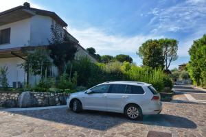 une voiture blanche garée devant une maison dans l'établissement Casa Maria, à Manerba del Garda
