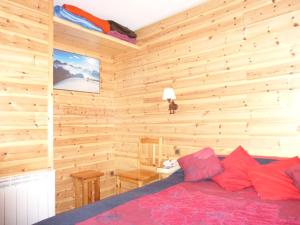 a bedroom with wooden walls and a bed with red pillows at Les Seolanes Pra Loup 520 in Pra-Loup